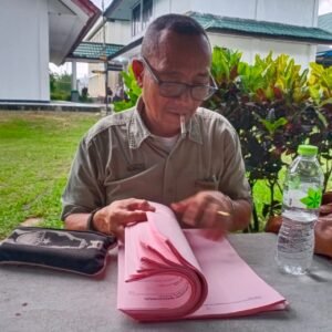 Caption: Rustam, SH selaku penasehat hukum keenam terdakwa perkara pencegahan dan pemberantasan perusakan hutan sedang melihat berkas tuntutan JPU Kejari Manokwari, I Dewa Gede Semara Putra, SH di PN Manokwari, Senin (13/4/2024). Foto: HEN